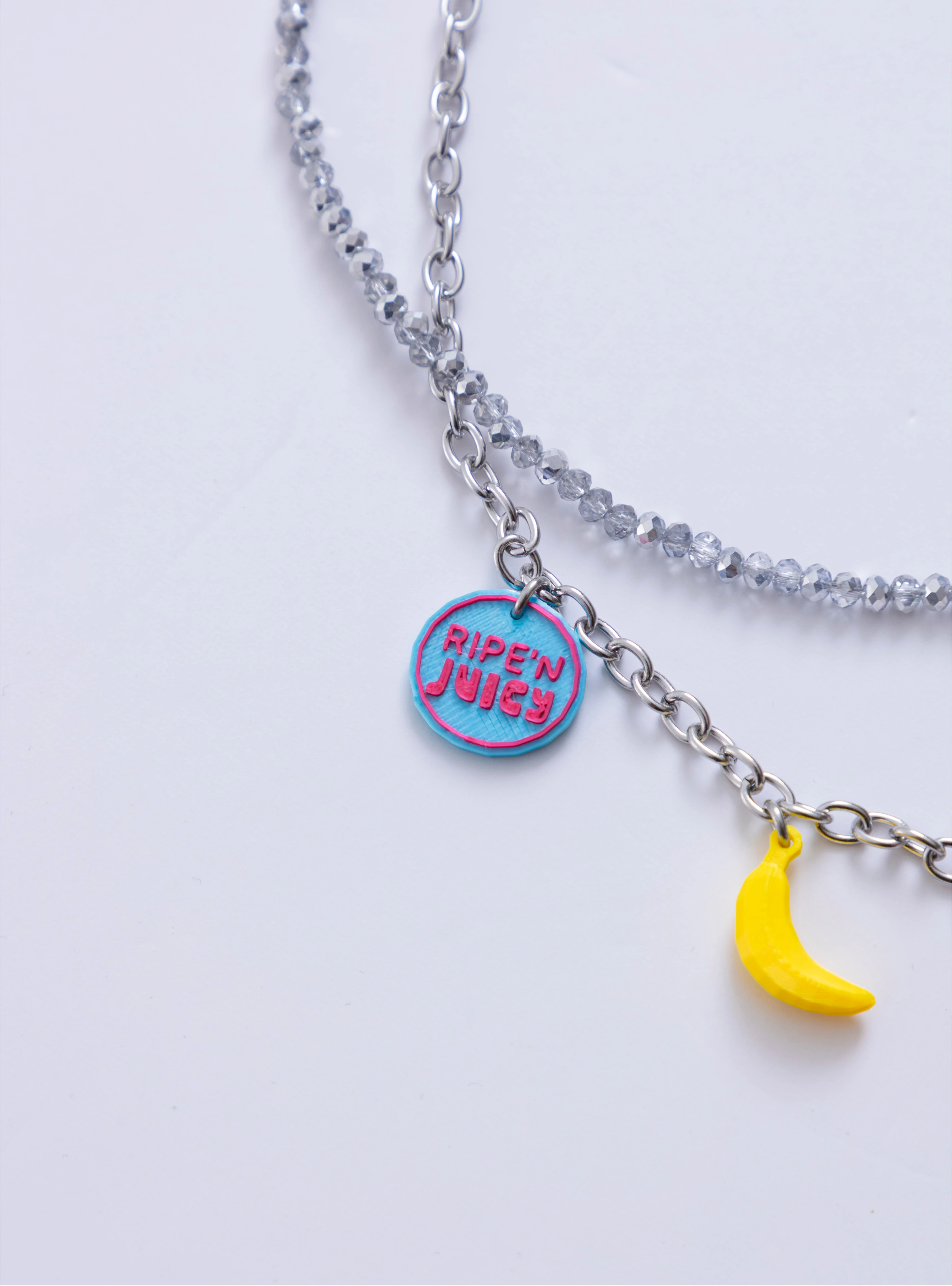 Detalle del dije Juicy Punch azul y charm de banano del Collar Juicy Punch Loft Me.