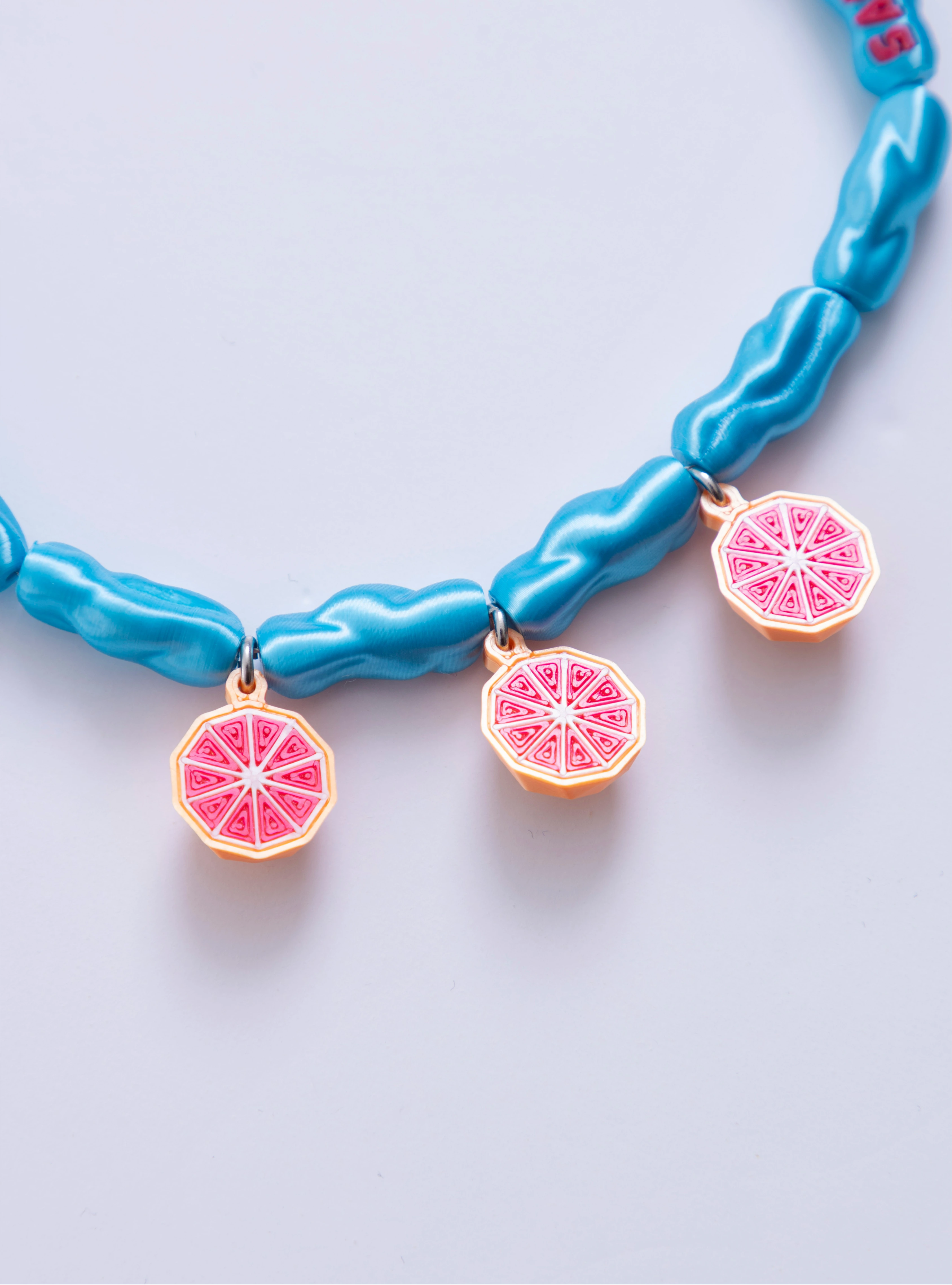 Detalle de los charms de toronjas 3D del Collar Alto en sabor Loft Me en eslabones azules.